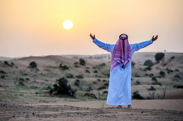 Retrato do homem árabe com sede no meio do deserto amarelo.