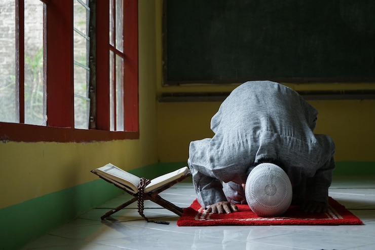 Foto retrato do homem muçulmano sujud ou prostração em um sajdah com alcorão e tasbih ao lado