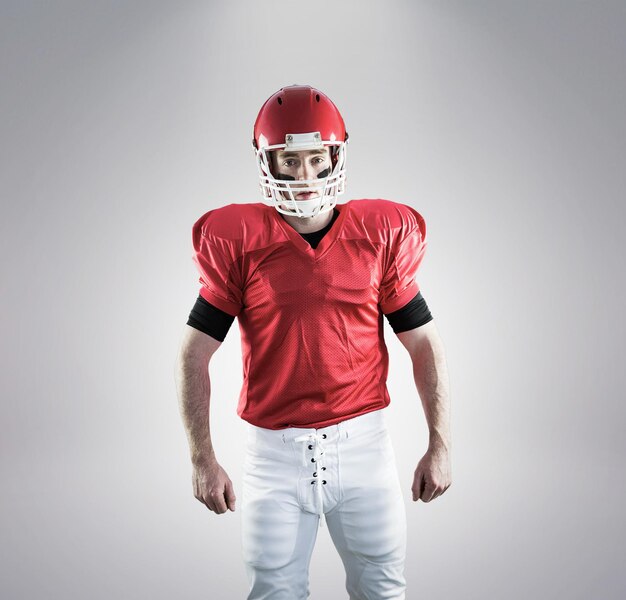 Foto retrato do jogador de futebol americano usando seu capacete contra fundo cinza