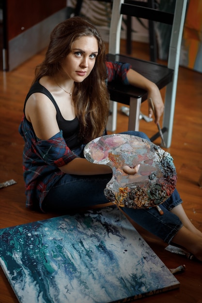 Foto retrato do jovem artista cercado por pinturas