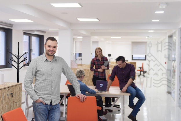 retrato do jovem empresário em roupas casuais no espaço de escritório de negócios de inicialização moderna, equipe de pessoas trabalhando juntas em segundo plano