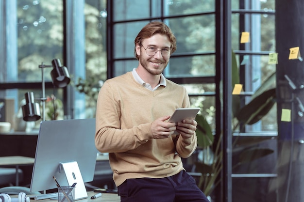 Retrato do jovem empresário homem loiro sorrindo e olhando para a câmera no trabalho em moderno