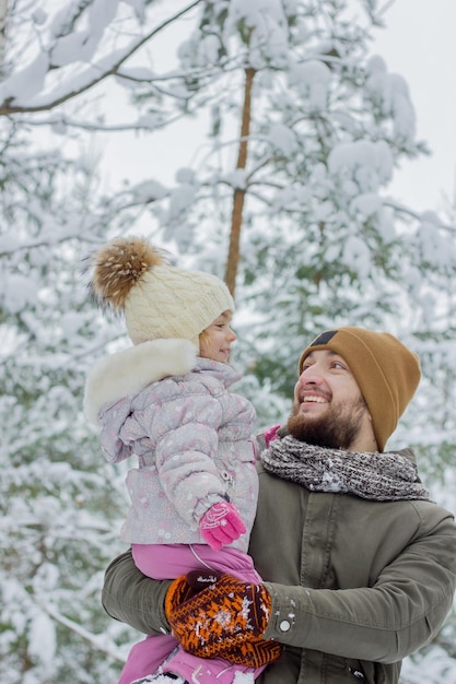 Retrato do jovem pai e sua filha ao ar livre com neve no inverno