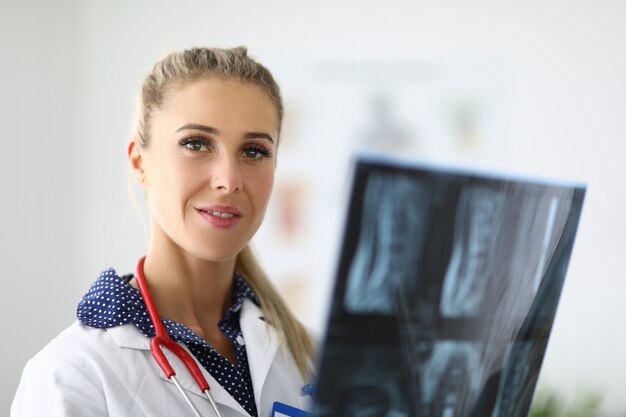 Retrato do médico com o estetoscópio nas mãos de um raio-x. Diagnóstico de pneumonia e conceito de pneumonia