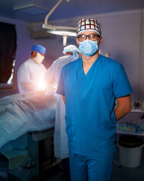 Retrato do médico em máscara e óculos. Grupo de cirurgiões na sala de cirurgia com equipamento de cirurgia. Formação médica. Foco seletivo