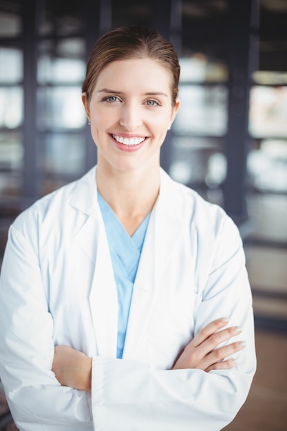 Retrato do médico feminino sorridente com os braços cruzados