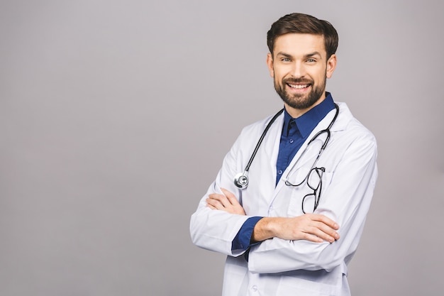 Retrato do médico jovem sorridente alegre com estetoscópio sobre o pescoço no casaco médico