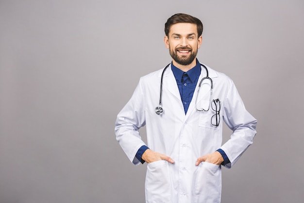 Retrato do médico jovem sorridente alegre com estetoscópio sobre o pescoço no casaco médico