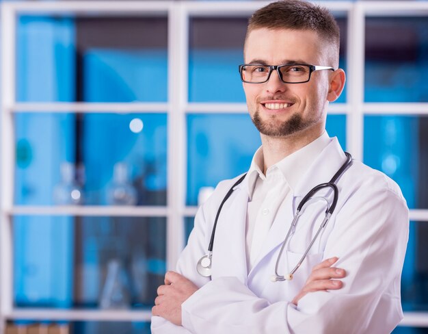 Retrato do médico masculino amigável está olhando para a câmera.