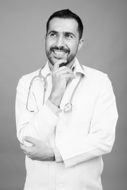 Retrato do médico persa barbudo bonito em cinza em preto e branco