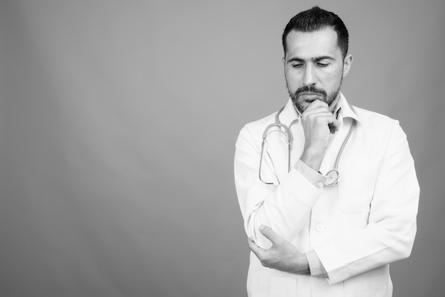 Retrato do médico persa barbudo bonito em cinza em preto e branco