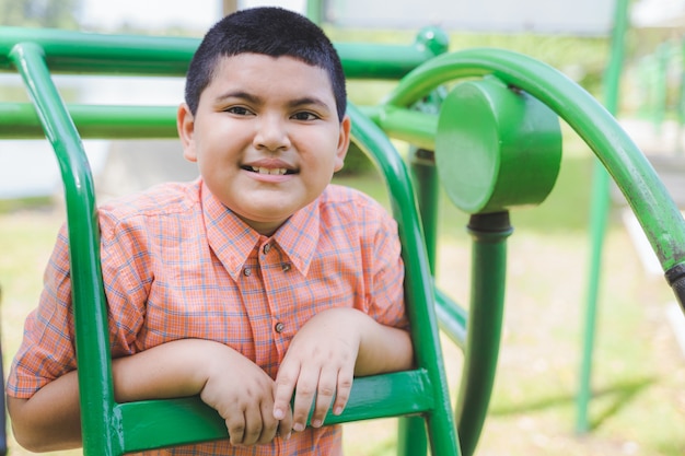 Retrato do menino asiático gordo bonito que joga no campo de jogos e que sorri à câmera