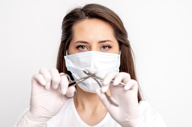 Retrato do mestre de manicure com máscara protetora branca segurando ferramentas de manicure em fundo branco