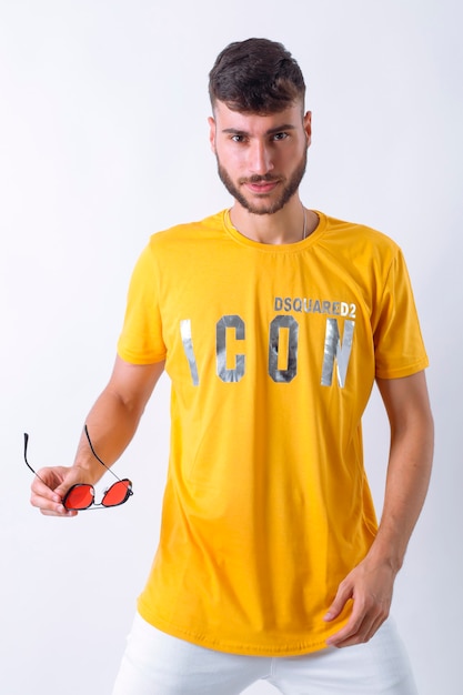 Foto retrato do modelo de jovem elegante e sorridente bonito vestido com a camiseta amarela pos.