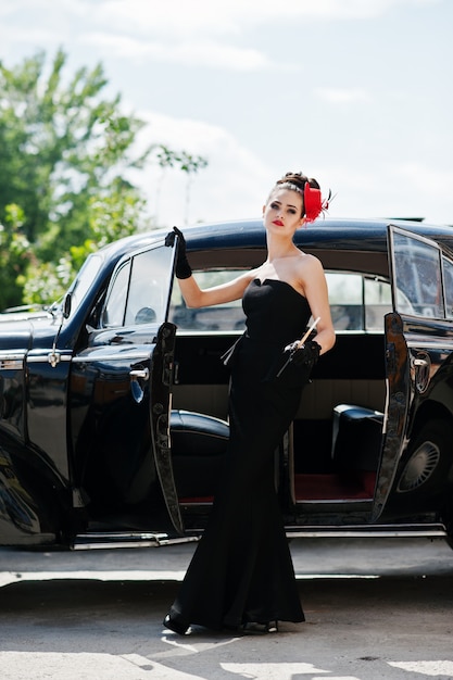 Retrato do modelo de menina moda morena sexy bonita com maquiagem brilhante em estilo retro perto de carros antigos com um cigarro na mão.