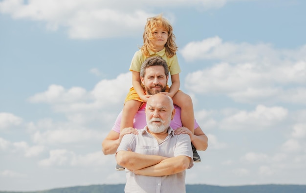 Retrato do pai do avô da geração dos homens e do neto ao ar livre no conceito do dia dos pais do céu homens eu