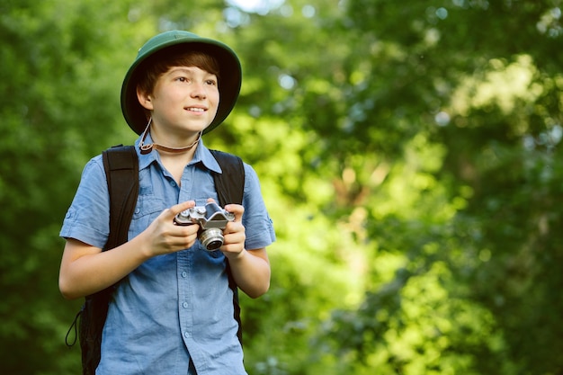 Retrato do pequeno explorador com câmera fotográfica na floresta