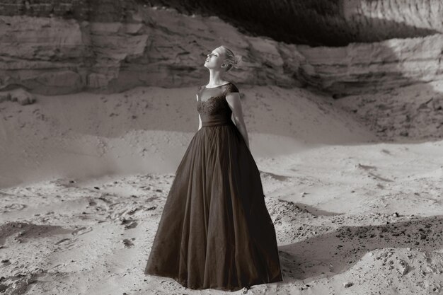 Retrato do perfil de uma bela jovem, em um vestido longo vermelho, posando em um deserto de areia.