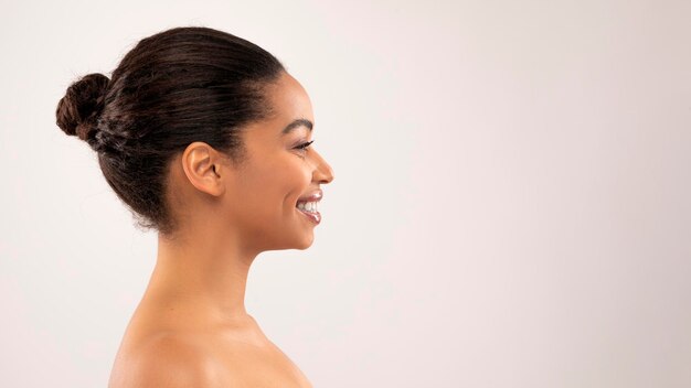 Foto retrato do perfil de uma linda mulher negra sorridente copiando o espaço