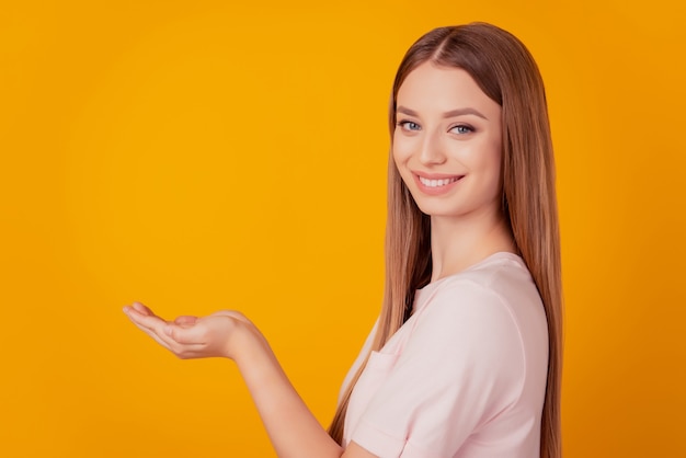 Retrato do perfil de uma senhora alegre e sorridente com as mãos segurando um objeto invisível sobre fundo amarelo