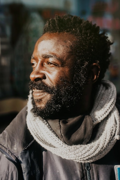 Retrato do perfil lateral de um homem negro sorridente em uma rua