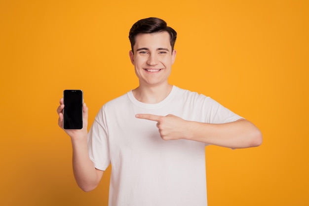 Retrato do promotor segurando telefone, dedo direto, tela sensível ao toque, espaço em branco sobre fundo amarelo
