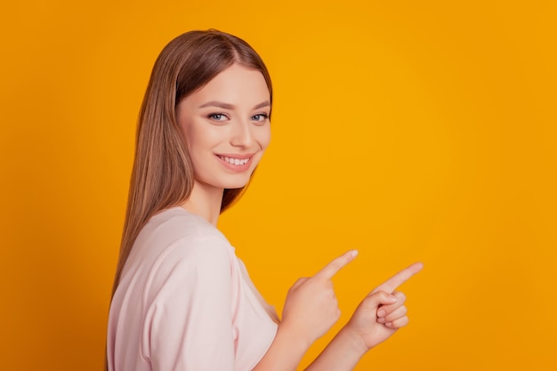 Retrato do promotor, senhora simpática, dedo direto no espaço vazio em fundo amarelo