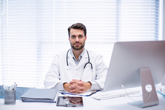 Retrato del doctor hombre sentado en el escritorio