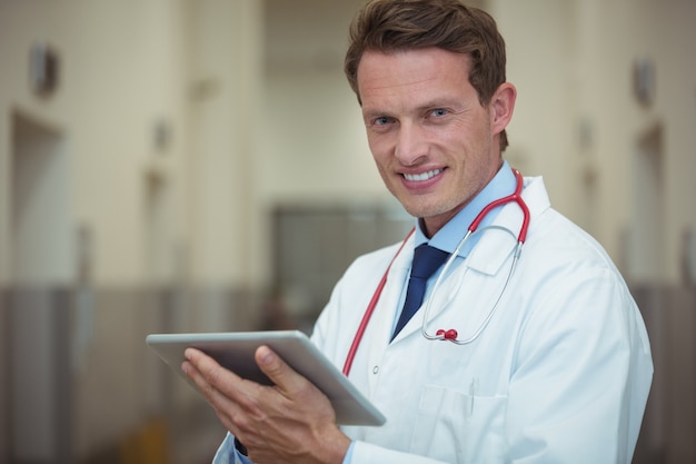 Retrato del doctor hombre usando tableta digital en corredor