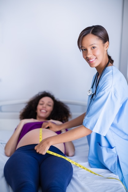 Retrato del doctor midiendo el vientre de la mujer embarazada en sala