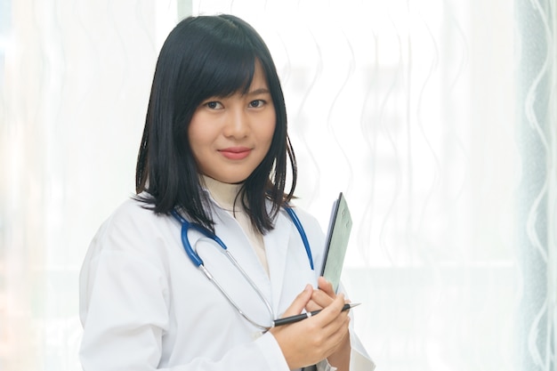 Retrato del doctor de sexo femenino asiático sonriente o feliz que lleva a cabo el documento en el fondo blanco.