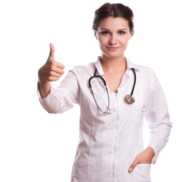 Retrato del doctor de sexo femenino joven sonriente feliz que muestra el letrero en blanco, con el gesto aceptable, aislado sobre blanco