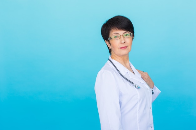 Retrato de doctora en bata blanca sobre azul con espacio de copia