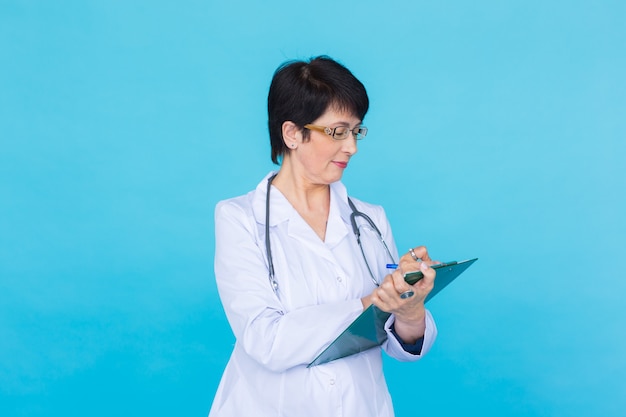 Retrato de Doctora escribiendo en el portapapeles sobre una pared azul