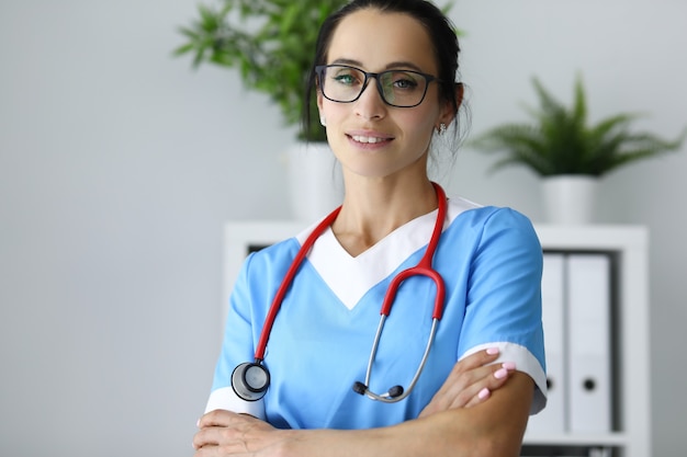 Retrato de doctora con gafas en consultorio médico.