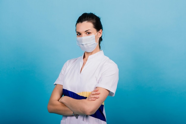 Retrato de una doctora con una máscara médica mirando hacia otro lado aislada en azul