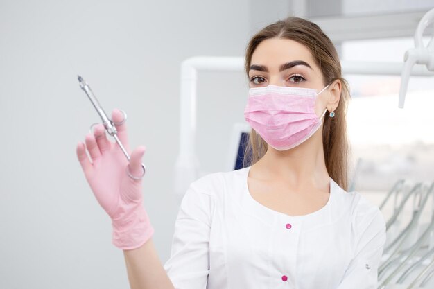 Retrato de una doctora con una máscara rosa en la cara con una jeringa en la mano