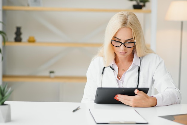 Retrato de una doctora de mediana edad que lleva una bata blanca de médico con un estetoscopio alrededor del cuello Médico sonriente de pie en una clínica privada