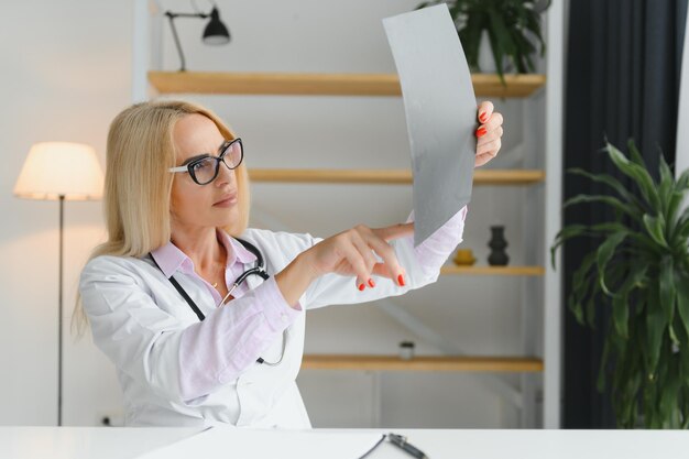 Retrato de una doctora de mediana edad que lleva una bata blanca de médico con un estetoscopio alrededor del cuello Médico sonriente de pie en una clínica privada