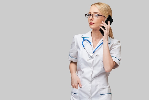 Retrato de una doctora o enfermera hablando por teléfono móvil