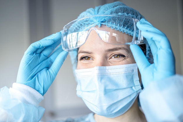 Retrato de una doctora que usa una máscara facial y una gorra para el trabajo de cirugía de los pacientes