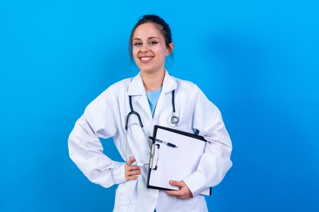 Foto retrato de una doctora sonriente con bata médica aislada en el concepto de medicina azul