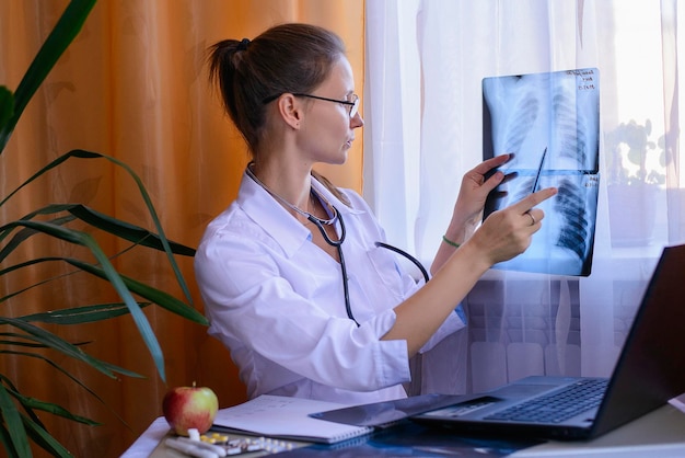 Retrato de una doctora sosteniendo una radiografía mientras está sentada en la mesa