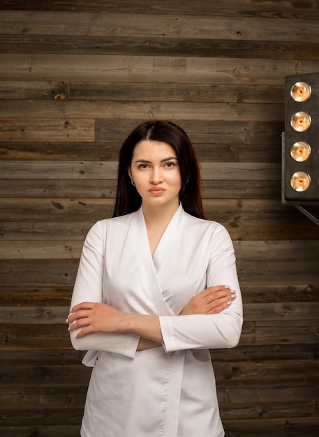 Retrato de una doctora en un uniforme blanco se encuentra en la pared de madera