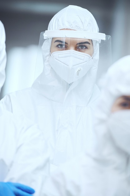 Retrato de doctora en uniforme protector y máscara mirando a cámara mientras trabajaba en el hospital