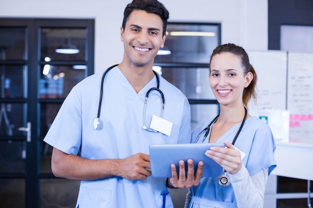 Retrato de los doctores que usan la tableta digital y sonriendo en el hospital