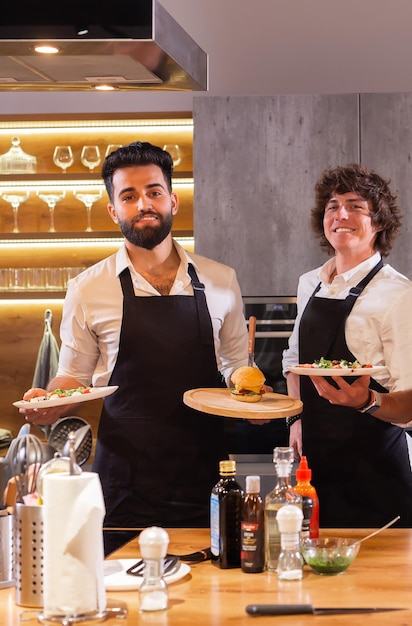 Retrato dois chefs felizes com refeições cozidas para um jantar na cozinha