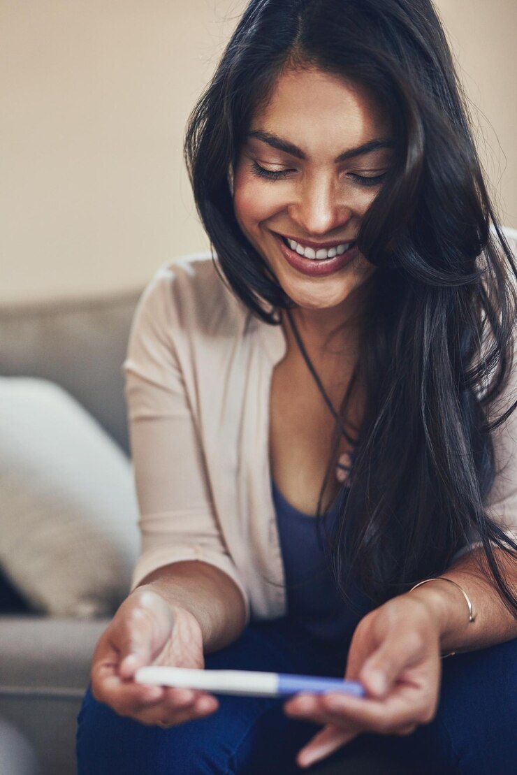 Foto retrato doméstico e felicidade de mulher com resultados de teste de gravidez e entusiasmada com a paternidade pessoa feminina e grávida com o primeiro bebê fertilidade e futura mãe no sofá na sala de estar