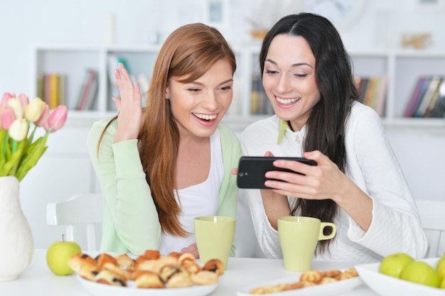 Retrato de dos amigas mirando smartphone