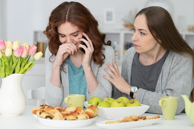 Retrato de dos amigas sentadas a la mesa y bebiendo té